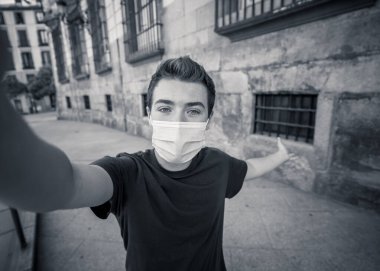 COVID-19 salgını. Şehirdeki genç adam koruyucu cerrahi maske takıyor ve arkadaşlarını ve ailesini cep telefonuyla arıyor. Yeni Normal ve zorunlu yüz maskesi kullanımında bağlı kalın.