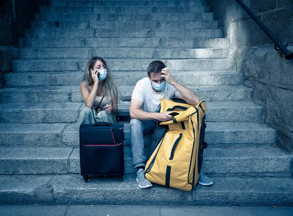 Sad tourist couple with mask and luggage ready for summer vacations trip worried about coronavirus test results and immunity passport. Vacations cancellations due to post covid travel restrictions.