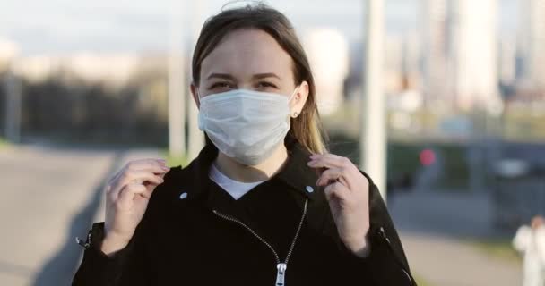 En kvinna tar av sig en medicinsk mask i staden. — Stockvideo