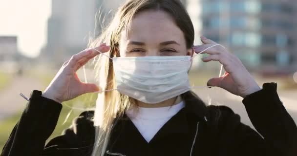 Retrato mujer pone en máscara médica de pie en la calle vacía de la gran universidad. — Vídeo de stock