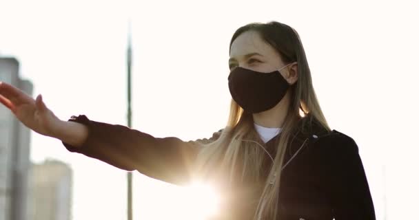 Μια γυναίκα με μαύρη ιατρική μάσκα κουνάει το χέρι της.. — Αρχείο Βίντεο
