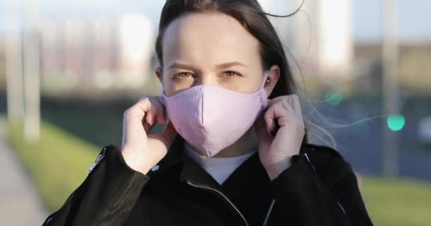 Una mujer feliz se quita una máscara médica brillante durante el día en la ciudad. — Vídeos de Stock