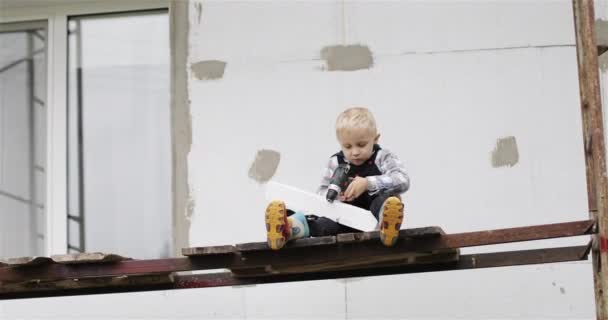 Menino feliz brincando com ferramentas em um canteiro de obras. — Vídeo de Stock