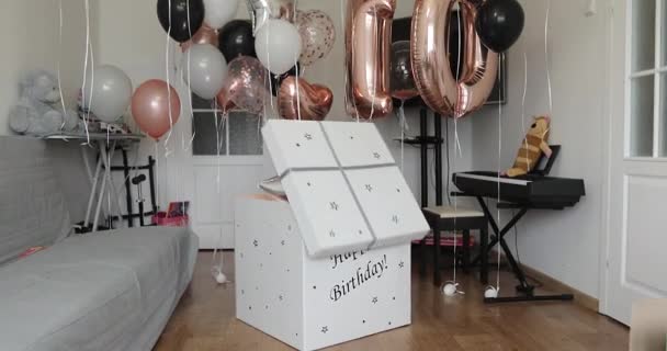 Una chica feliz con globos salta de una caja de cartón. — Vídeos de Stock