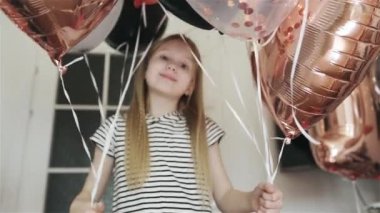 Güzel bir kız, arka planda güzel balonların kalbini gösterir..