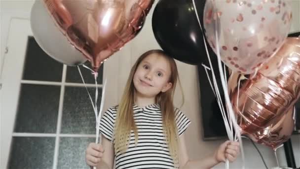 Dziewczyna pokazuje serce z rękami na tle balonów. — Wideo stockowe