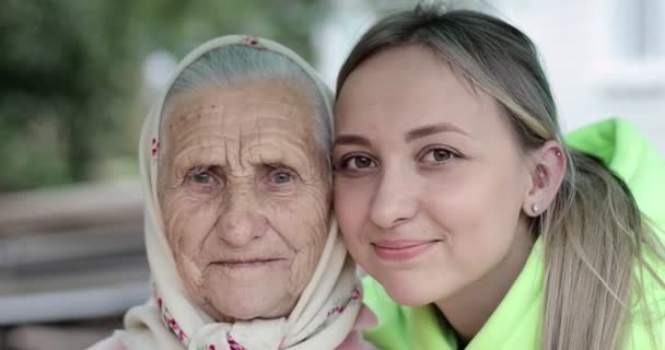 Лицо бабушки с глубокими морщинами и улыбающаяся молодая женщина. — стоковое видео