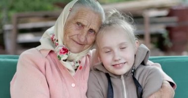 Yaşlı bir kadın, kırışıklıkları derin ve küçük bir kız sarılıyor..