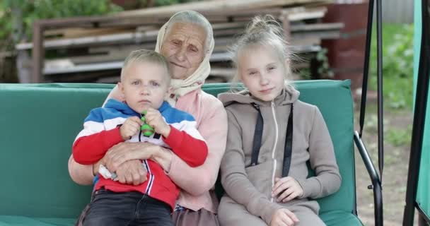 Büyükanne ve torunları salıncakta oturuyor.. — Stok video