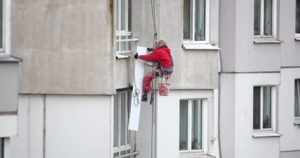 Un grimpeur répare une fenêtre dans un immeuble de grande hauteur de la ville. — Video