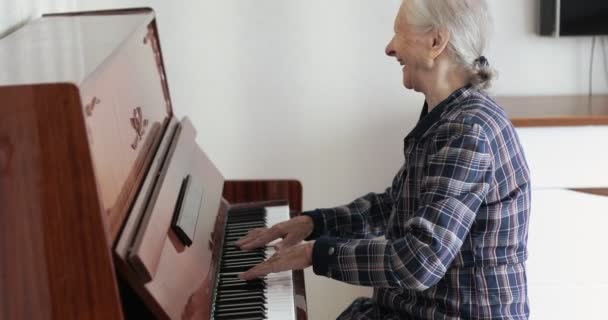 Egy ősz hajú idős hölgy zongorázik.. — Stock videók
