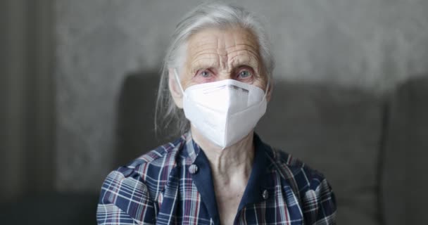 Mulher idosa com máscara de proteção respiratória fica em casa. — Vídeo de Stock