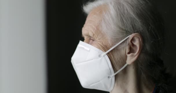 Närbild ansikte av en gammal mormor med djupa rynkor i en medicinsk mask. — Stockvideo