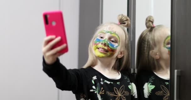 Skolejente med ansiktsmaling lager en selfie. – stockvideo