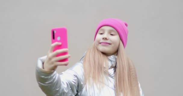 Seorang gadis dengan topi merah muda tersenyum untuk selfie. — Stok Video