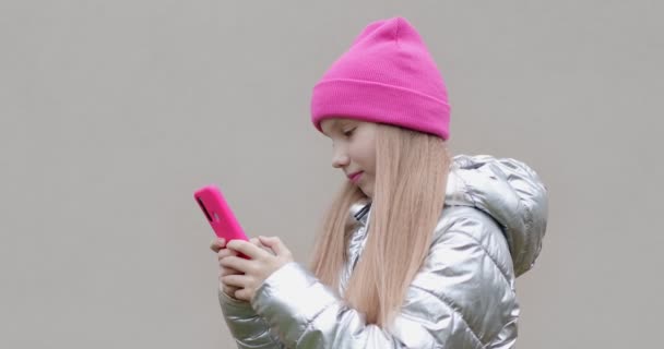 Uma estudante com um chapéu rosa está digitando uma mensagem em um telefone celular na cidade. — Vídeo de Stock