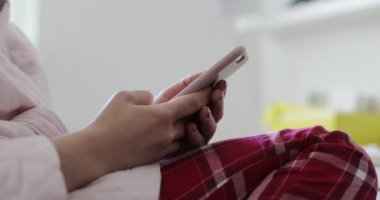 Evde cep telefonu kullanan pijamalı bir kadın.. 