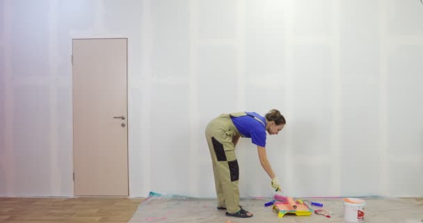 Pintor mujer en el trabajo pintando una pared naranja con un rodillo, vista trasera. — Vídeos de Stock