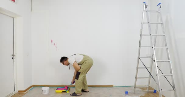 Painter man dips roller into a plastic pallet with pink paint. — Stock Video