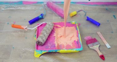 Turuncu boya yakın plan, boya silindiriyle plastik bir palete akıyor..
