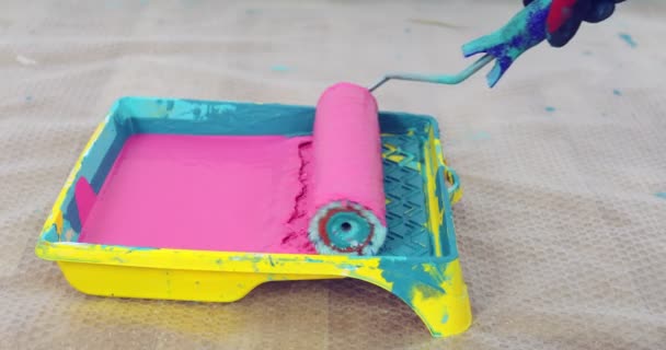 Close-up painter man dips roller into a plastic pallet with pink paint. — Stock Video