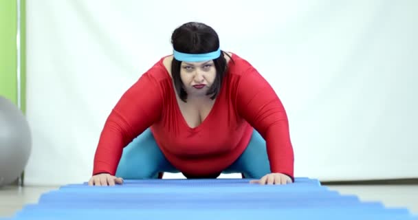 Fet kvinna lägger sig på träningsmattan. — Stockvideo