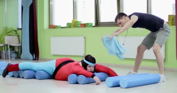 Fatigué grosse femme se trouve sur les rouleaux de gymnastique dans la salle de gym. — Video