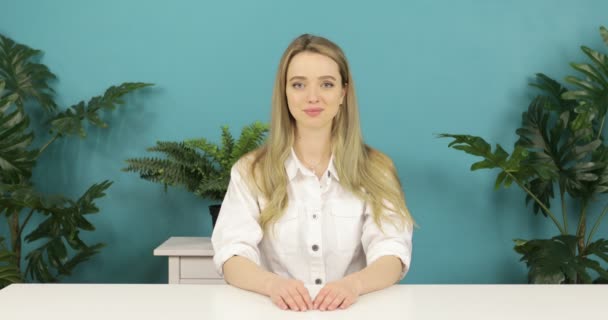 Portret van een aantrekkelijk blond meisje met lang haar aan tafel. — Stockvideo