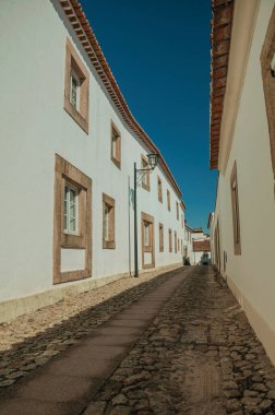 Facade of old whitewashed houses and cute windows in cobblestone alley, on a sunny day at Marvao. An amazing medieval fortified village in Portugal.