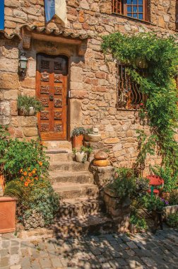 Draguignan yakınlarındaki Les Arcs-sur-Argens 'ın ortaçağ köyünde bindweed ve merdiven ile taştan ev cephesine yakın çekim. Provence bölgesi, Fransa.