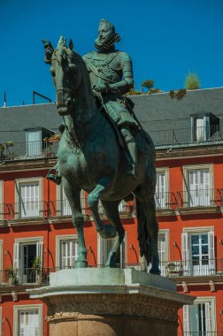 Madrid 'de güneşli bir günde Plaza Mayor meydanında ve eski binalarda Kral III. Philip' in bronz atlı heykeli. İspanya 'nın büyüleyici başkenti.