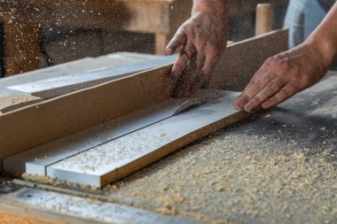 Bir marangoz, makine aletinin ahşap işçiliğinde çalışır. Marangoz, marangoz dükkanında marangozluk yapıyor..