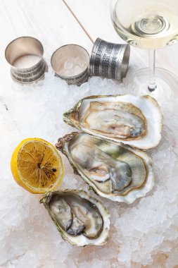 Buzlu limonlu taze istiridye ve bir kadeh şarap.