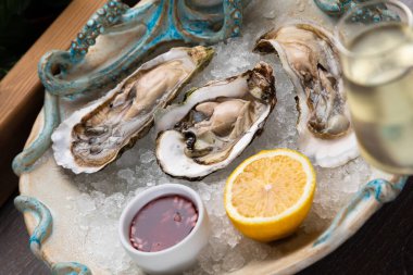 Sos, limon ve bir bardak şaraplı taze istiridye.