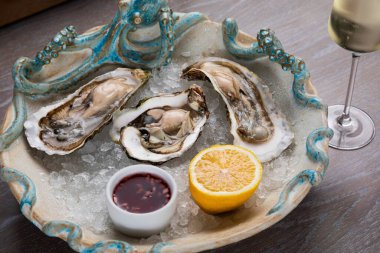 Sos, limon ve bir bardak şaraplı taze istiridye.