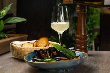 Kremalı soslu midye, kızarmış ekmek ve bir bardak şarap.