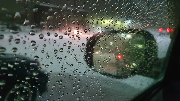Water drops on the car window glass in the evening in the city