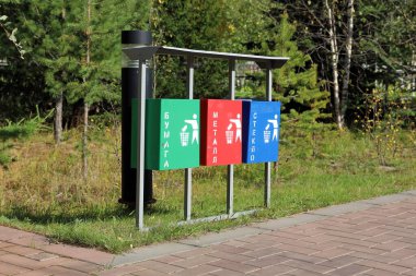 Şehir parkında ayrı atık toplama için vazolar var. Üzerinde Rus kağıdı, metal, cam yazılar var.
