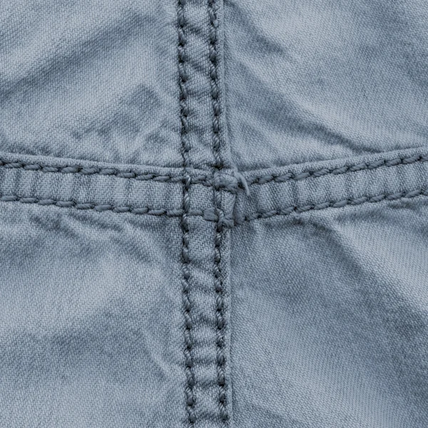 Blue crumpled denim texture decorated with seams — Stock Photo, Image