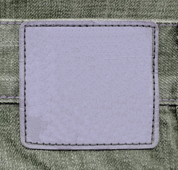 Leather label on green jeans background — Stock Photo, Image