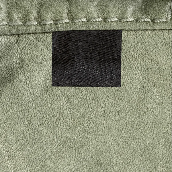 Textura de couro verde claro, costura, etiqueta preta em branco — Fotografia de Stock