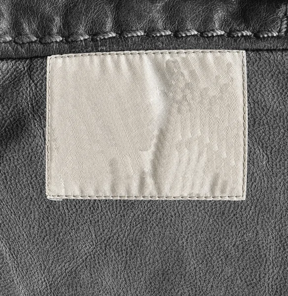 Textura de couro preto, costura, etiqueta em branco — Fotografia de Stock