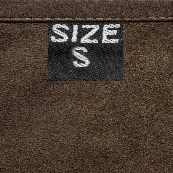 Brown leather texture closeup, tag, size. — Stock Photo, Image