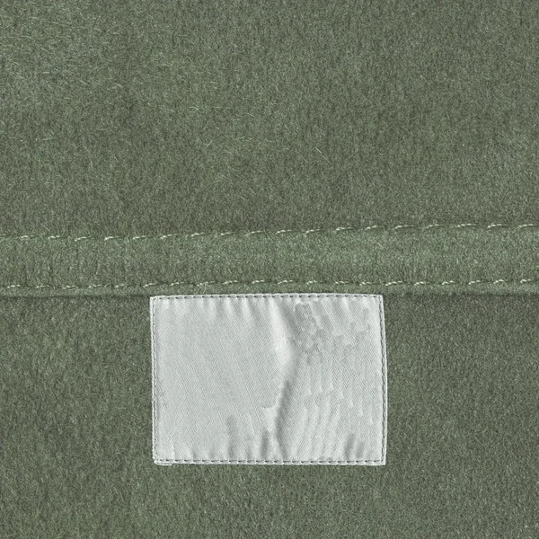 Textura de cuero verde, costura, etiqueta blanca en blanco — Foto de Stock