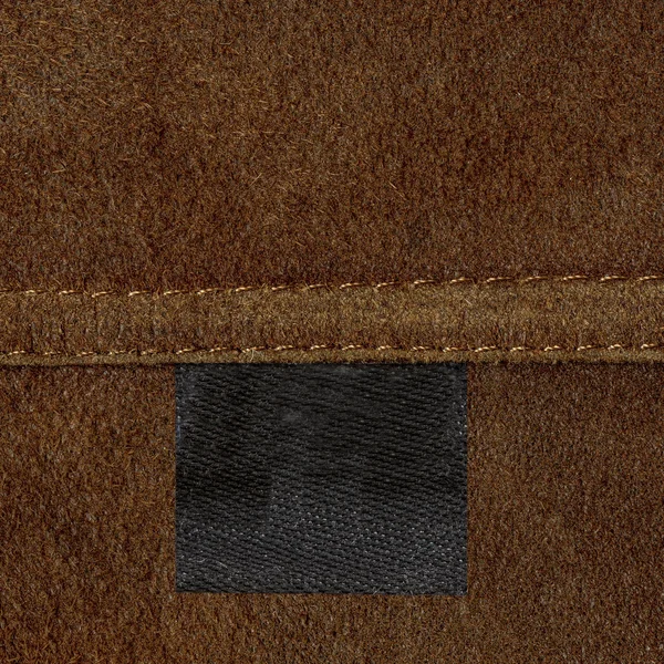 Brown leather texture, seam, black blank tag — Stock Photo, Image