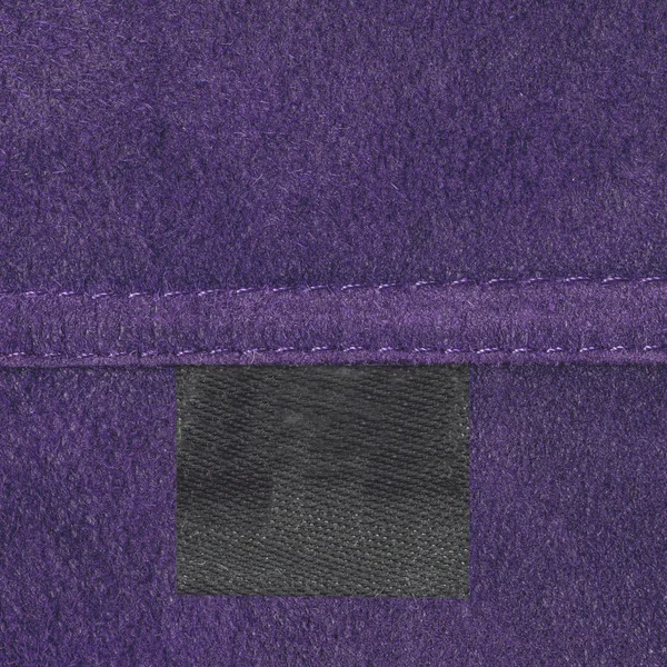 Violet leather texture, seam, black blank tag — Stock Photo, Image