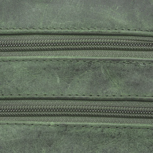 Yeşil deri arka plan iki fermuar ile dekore edilmiştir. — Stok fotoğraf