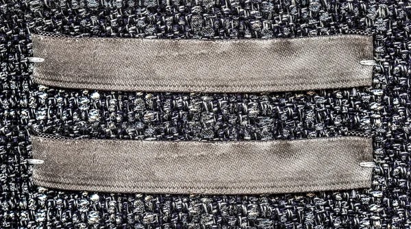 Etiquetas têxteis castanhas em branco sobre fundo têxtil cinzento — Fotografia de Stock