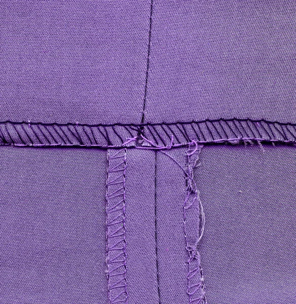 Mauvais côté couture pantalon, fond textile violet — Photo