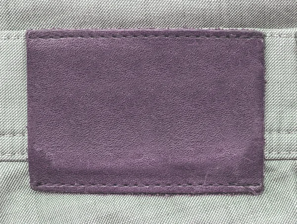 Порожній фіолетовий шкіряний ярлик на фоні джинсів — стокове фото